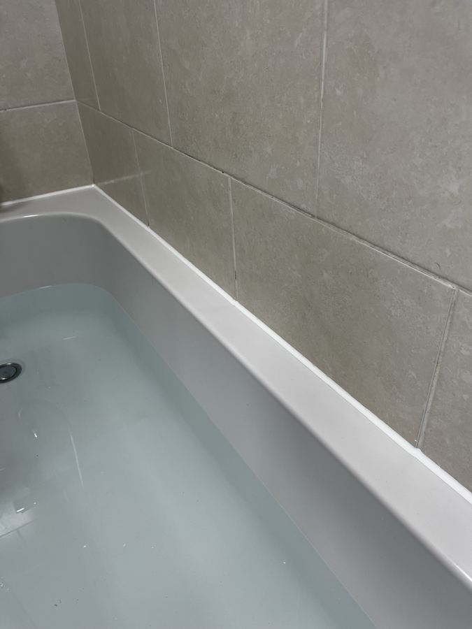 Bath perimeter sanitary sealant replacement in Baildon - failed, mouldy bead removed and replaced.