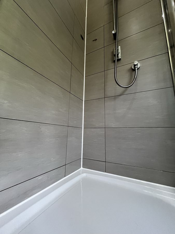 Replaced shower sealant in a Harrogate property - neat new sanitary-grade silicone after full removal of failed bead.