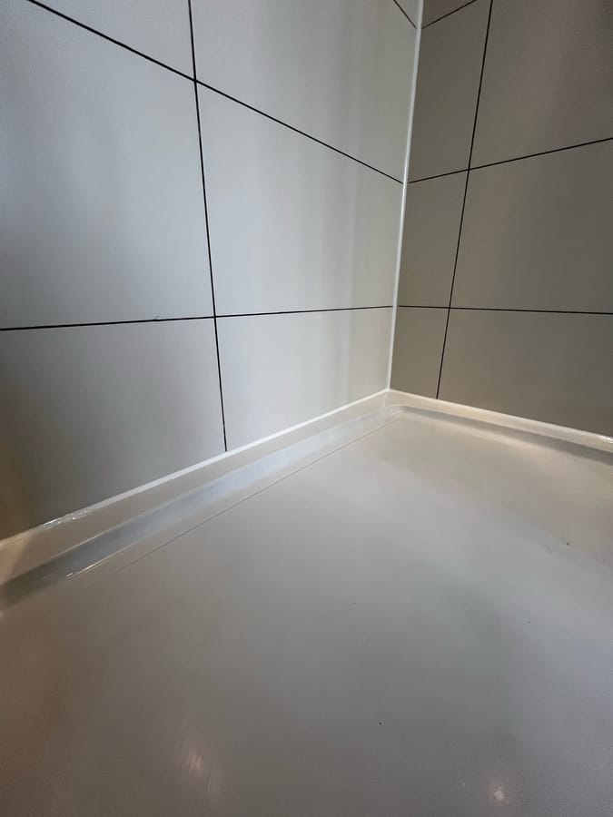 After: new white sanitary silicone bead along a shower tray and tiled corner, Harrogate